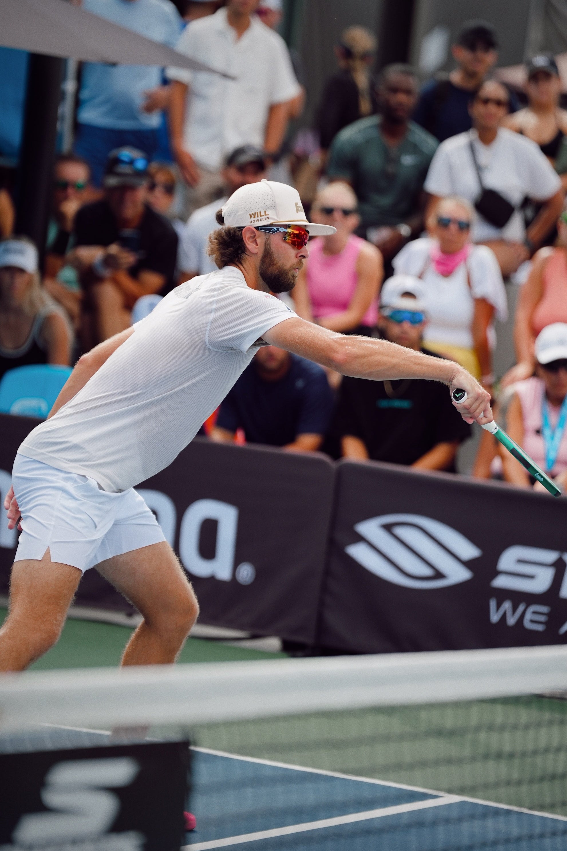 Pickleball player in action on a court with spectators in the background