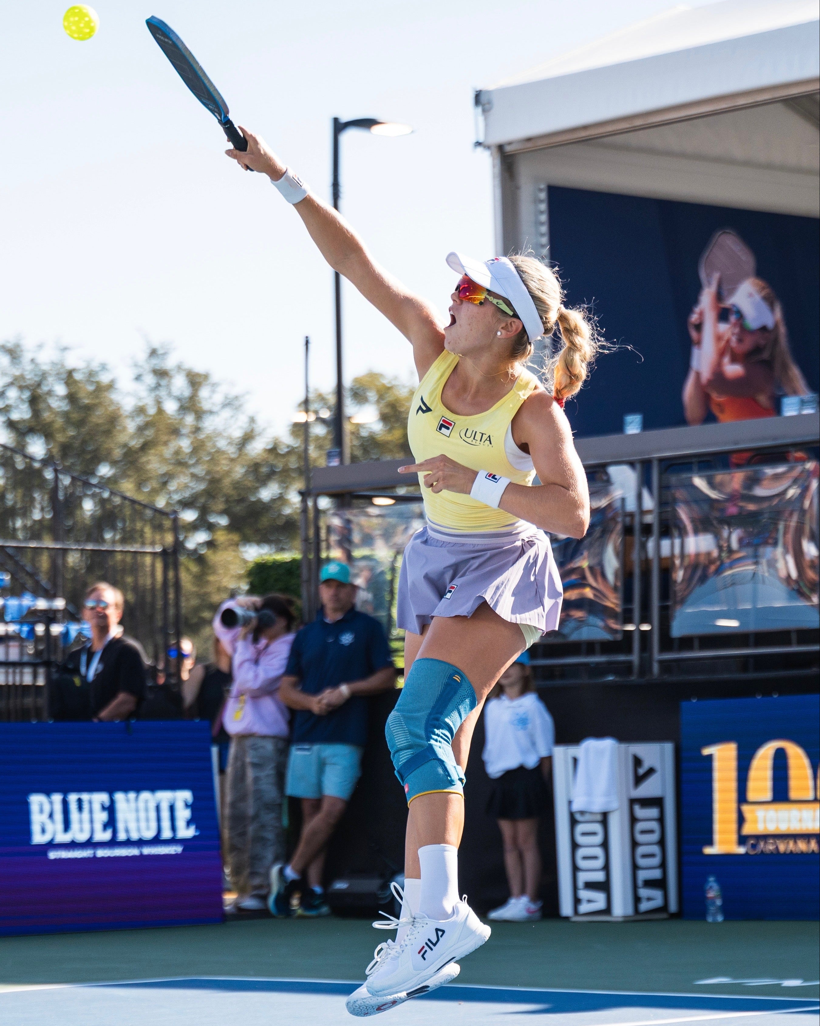 Pickleball player in action on a court with spectators and advertisements in the background